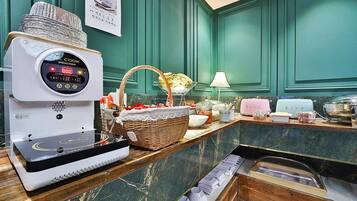 Una cocina con placa de inducción, un cesto de plátanos y diversos utensilios de cocina.