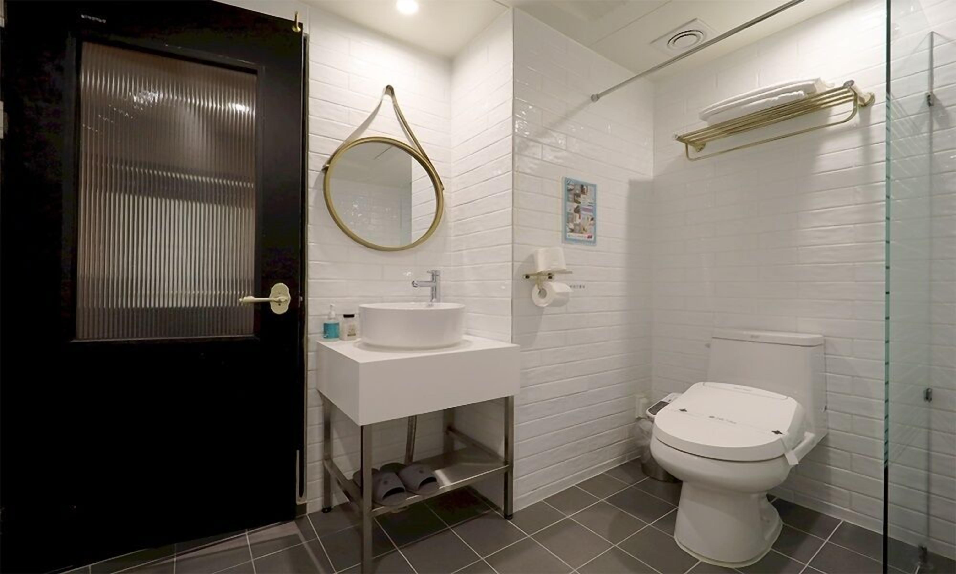 A bathroom with a toilet, sink, and mirror.