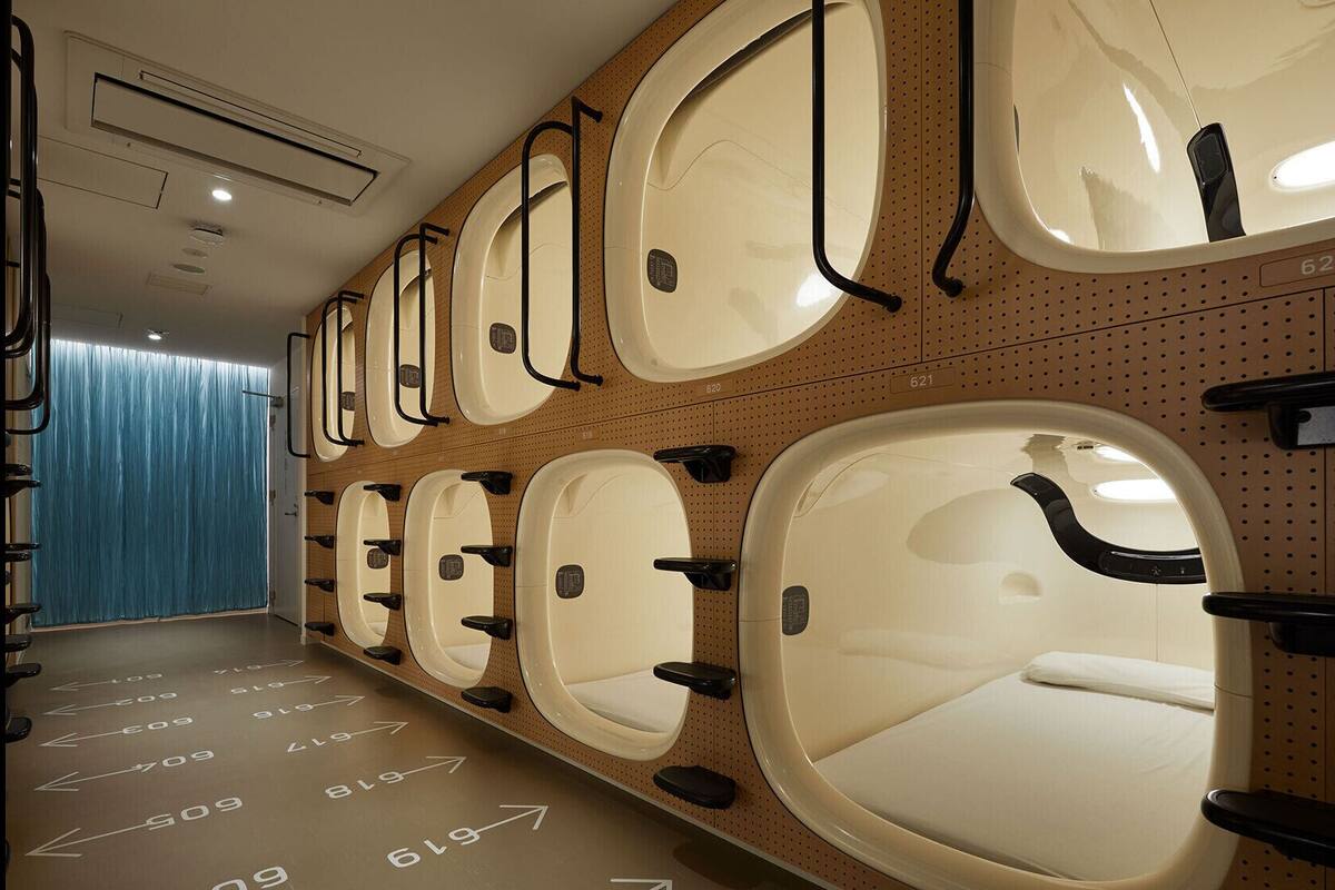 Une rangée de toilettes de forme ovale, chacune équipée d’un lavabo et d’un miroir individuels, et portant un numéro d’identification.