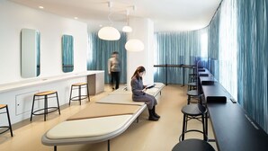 A modern waiting area with a long bench, individual chairs, and a reception desk. - 9h nine hours Ningyocho (Tokyo)