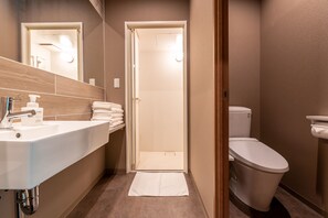 Un baño moderno con lavamanos, inodoro y espejo.