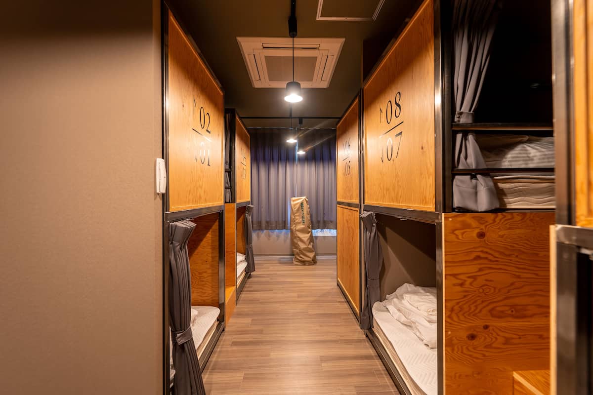 A narrow corridor with bunk beds, wooden walls, and a curtain in the background.
