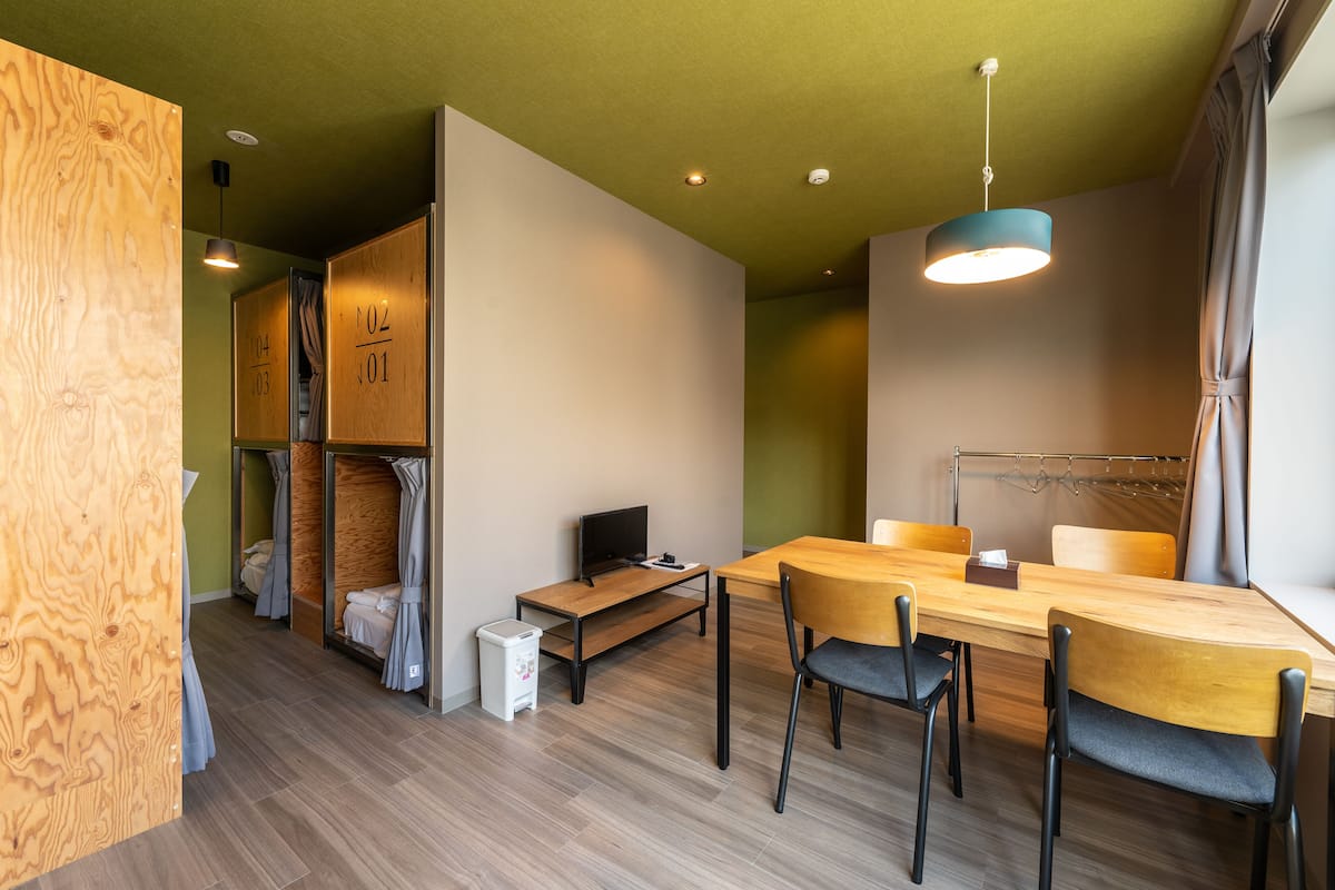 A modern room with a wooden desk, two chairs, a TV, and a small trash bin.