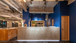 A reception area with a concrete counter, wooden cabinets, and a 'Staff Only' door. - WISE OWL HOSTELS SAPPORO (Sapporo)