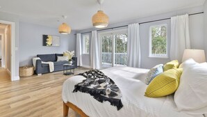 A bedroom with a large bed, a sofa, and a balcony.