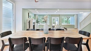 A spacious dining area with a long wooden table, black chairs, and a ceiling fan.