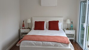 A modern bedroom with a large bed, white walls, and a wooden floor. - Secluded Pool House getaway- 500m to patrolled Shelly Beach (Shelly Beach)