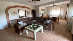A living room with a brown sofa, a glass coffee table, and a ceiling fan. - Casa las Chorreras del Orejón 1 (CORDOBA)