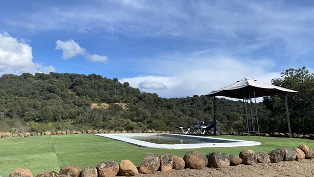 A golf course with a putting green, a pavilion, and a rocky border. - Casa las Chorreras del Orejón 1 (CORDOBA)