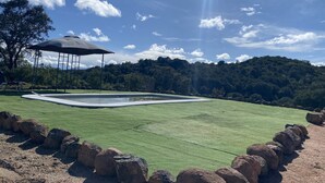 A pool with a surrounding rock border, a gazebo, and a forested hillside in the background. - Casa las Chorreras del Orejón 1 (CORDOBA)
