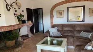 A living room with a brown leather sofa, a glass coffee table, a fireplace, and a mirror on the wall. - Casa las Chorreras del Orejón 1 (CORDOBA)