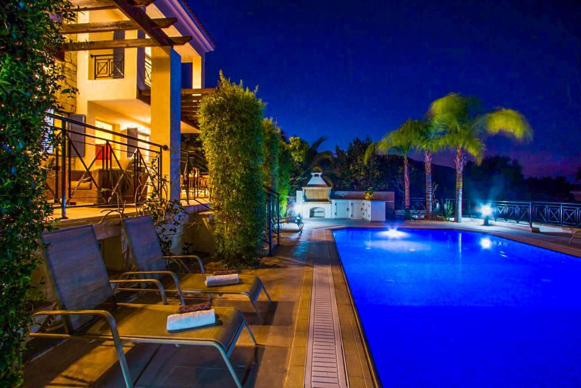 Zona de piscina al aire libre con sillas de descanso y un edificio al fondo.