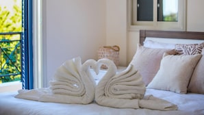 Een bed met twee handdoeken in de vorm van zwanen en uitzicht op een balkon.