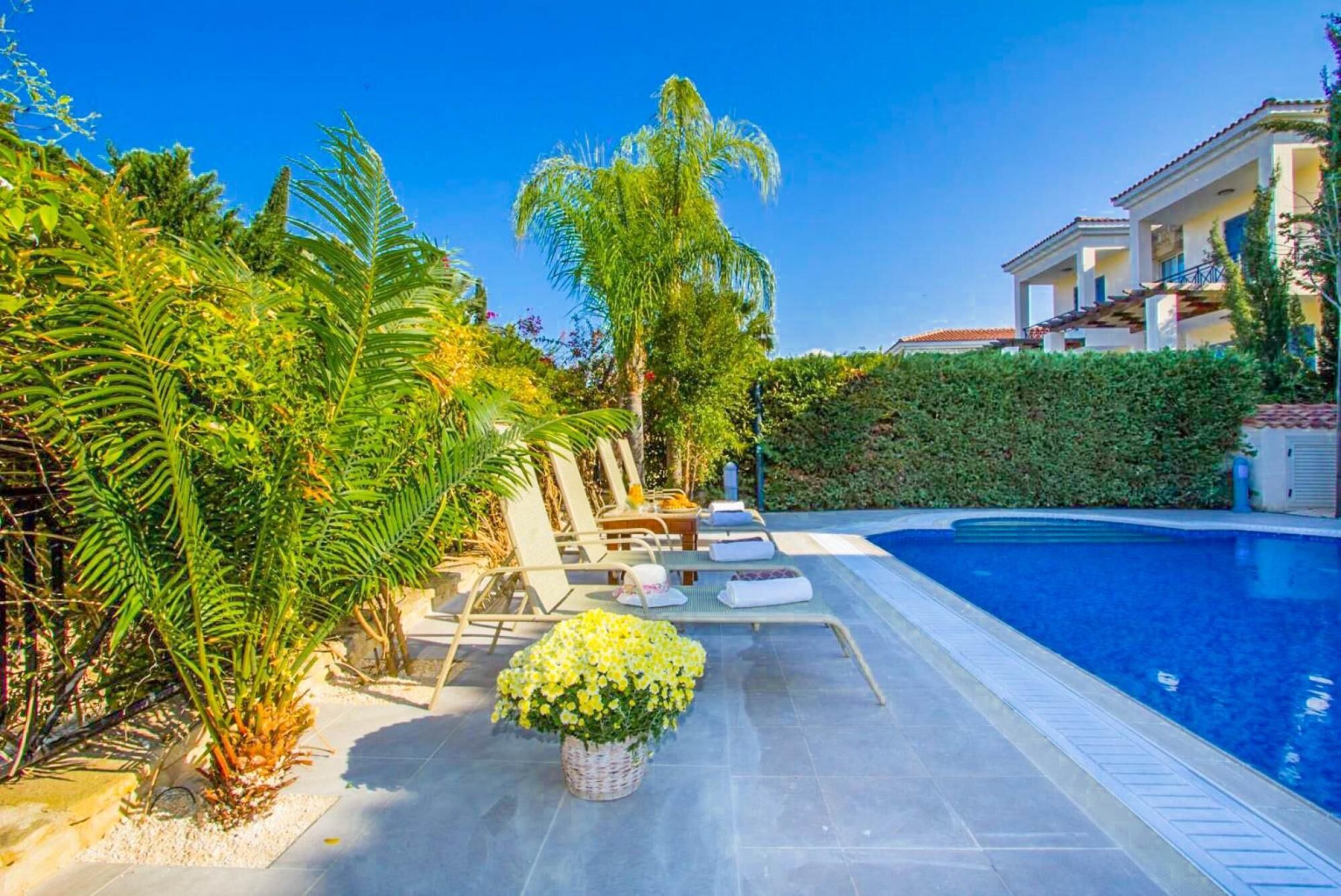 A pool area with lounge chairs and a small flower arrangement.