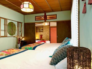 A hotel room with a large bed, a wicker chair, and a hanging light fixture. - TSUDOYA Tsukamoto (Osaka)