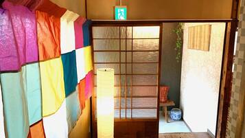 A traditional Japanese room with tatami flooring, a shoji screen door, and a hanging lantern.