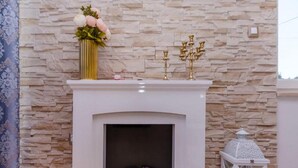 A fireplace with a stone wall backdrop, a vase with flowers, and a white lantern. - Villa Antica (Rogoznica)