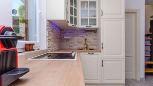 A modern kitchen with white cabinetry, a stone backsplash, and a built-in sink. - Villa Antica (Rogoznica)