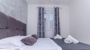 A modern hotel room with a large bed, a smaller bed, and a window with patterned curtains. - Villa Antica (Rogoznica)