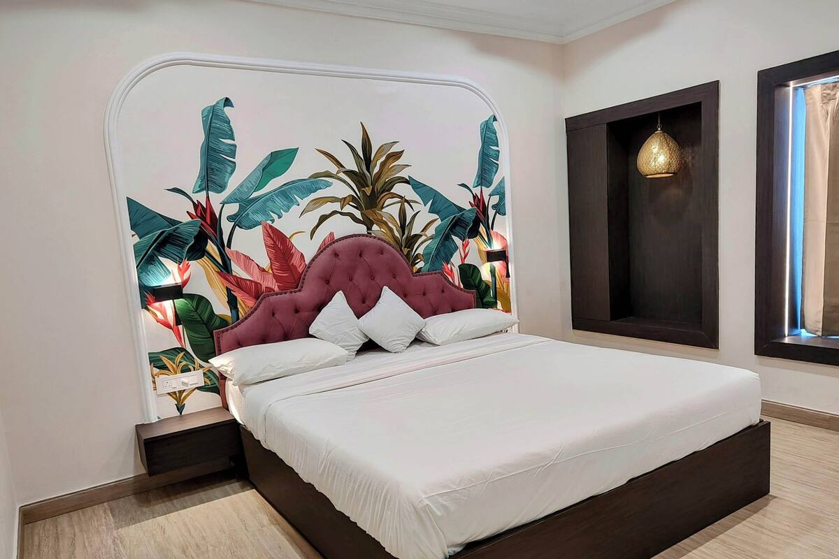 A modern bedroom with a large bed, a decorative headboard, and a wall-mounted light fixture.