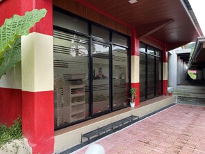 A building with large windows, a red and white facade, and a brick pathway leading to the entrance. - Paradise Adventure Camp 3 & Resort by Cocotel (San Jose del Monte)