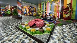 Habitació amb terra de rajola, llit amb llençol de punts i un petit pont, i una paret decorada amb tires verticals de colors i composicions florals.