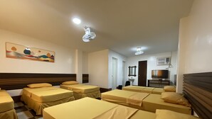 Habitació d'hotel amb diversos llits, televisió, un vàter i un mirall.
