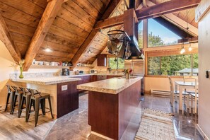 A kitchen with a large island, bar stools, and a view through the windows.