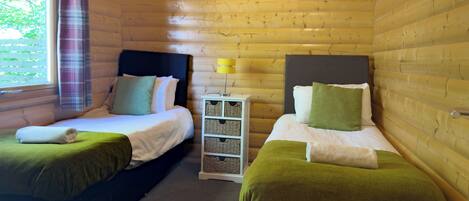 A cabin with two beds, a nightstand, and a window with curtains.