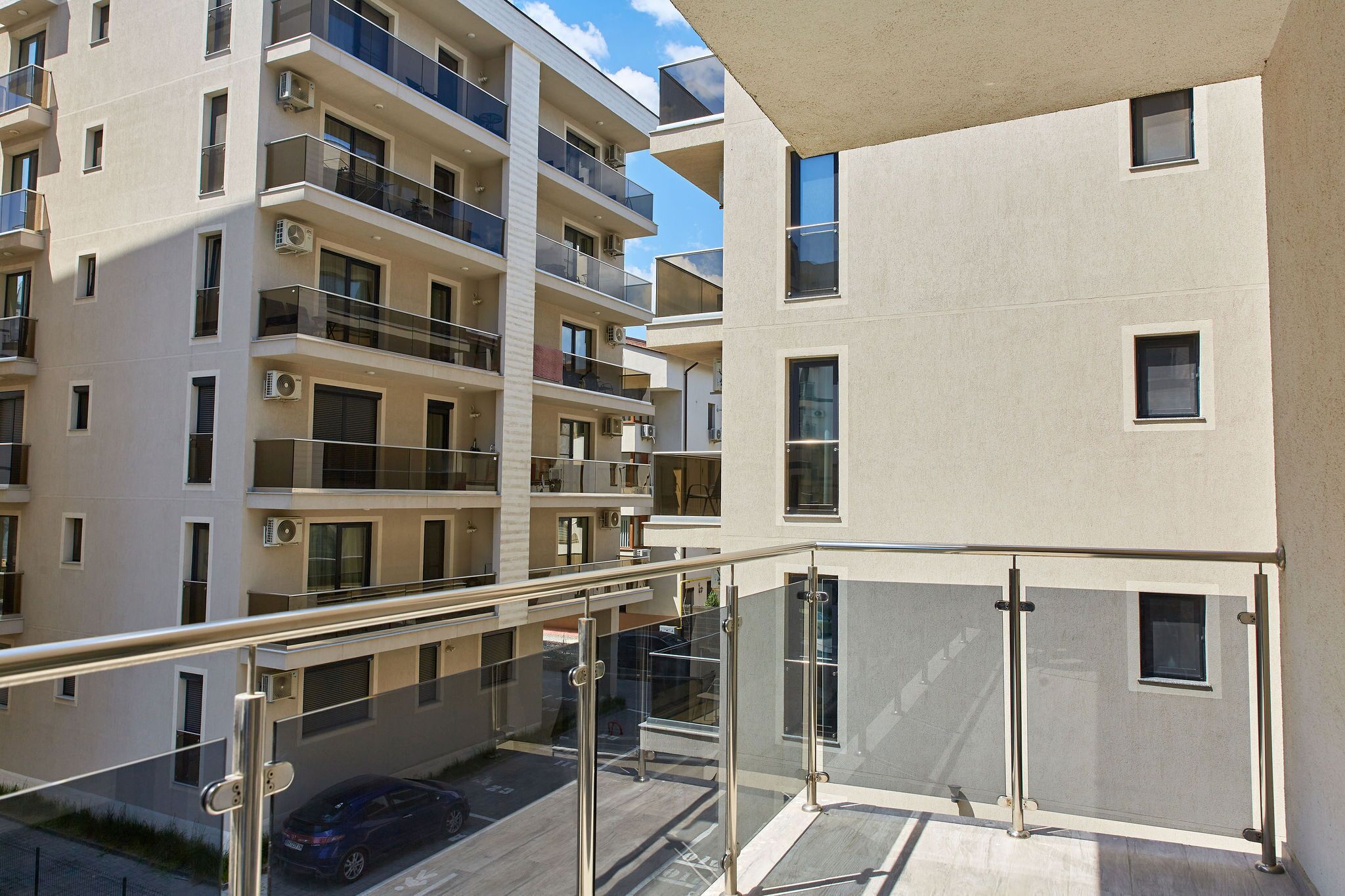 A multi-story residential building with balconies, large windows, and a clear sky.