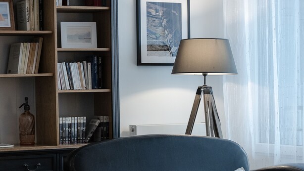 A modern living room with a dark blue sofa, a bookshelf, a lamp, and a framed picture on the wall. - Cosy, comfortable apartment in the city center (Caen)