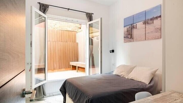 Une chambre à coucher comprenant un lit, une table et une porte coulissante donnant sur une salle de bain.