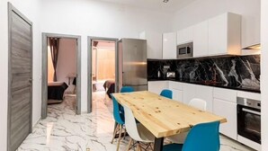 Une cuisine compacte avec des meubles blancs, un pare-feu en marbre et une table à manger en bois, assortie de chaises bleues.