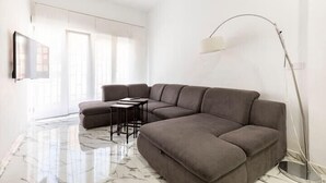 Un salon moderne avec un canapé d’angle, une table basse et un lampadaire.