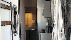 Un pasillo estrecho que conduce a un baño con lavamanos y espejo.