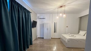 Una habitación de hotel moderna con una cama, un armario, un escritorio y un televisor.
