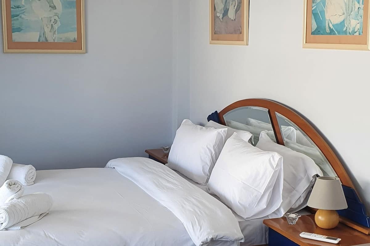 A neatly arranged bedroom with a bed, bedside table, lamp, and a bench.