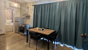 Una cocina moderna con comedor, que incluye una mesa y sillas de madera, horno empotrado y una lámpara colgante.