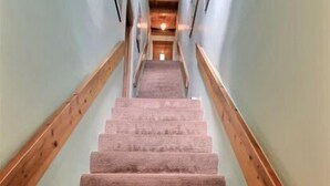 A carpeted staircase with wooden handrails and a light-colored wall. - Spacious, Well Stocked Condo in the Foothills (Valdez)
