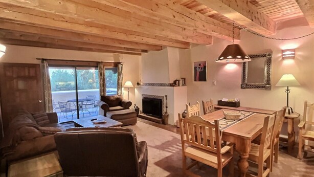 A cozy living room with a fireplace, wooden dining table, and comfortable seating. - Spacious, Well Stocked Condo in the Foothills (Valdez)