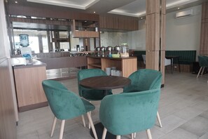 A modern kitchen with a central island, green upholstered chairs, and a dining table.