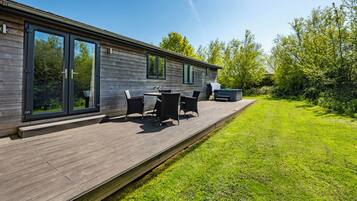 A modern house with a deck, sliding glass doors, and a lawn.