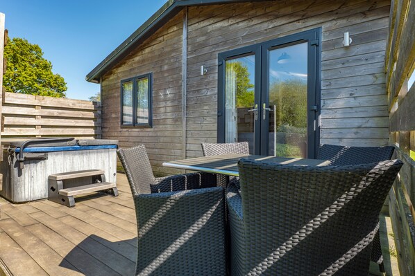 A wooden deck with outdoor furniture, a hot tub, and a sliding glass door to a covered patio. - Warren Wood Country Park (Pevensey)