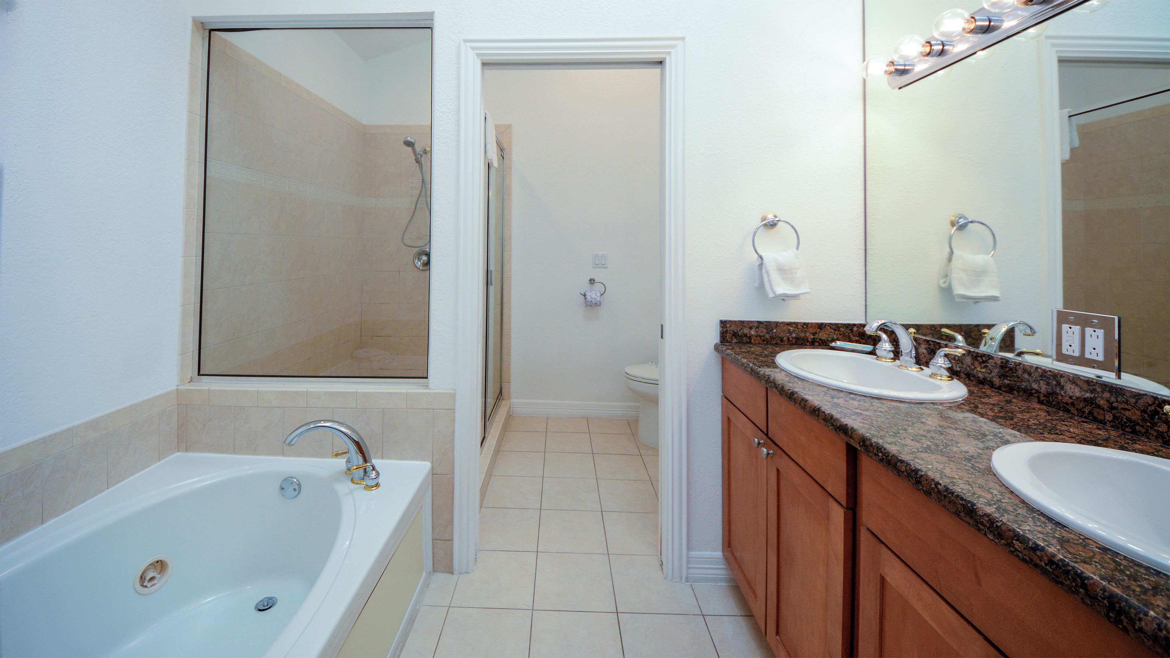 A bathroom with a bathtub, two sinks, a shower, and a large mirror.