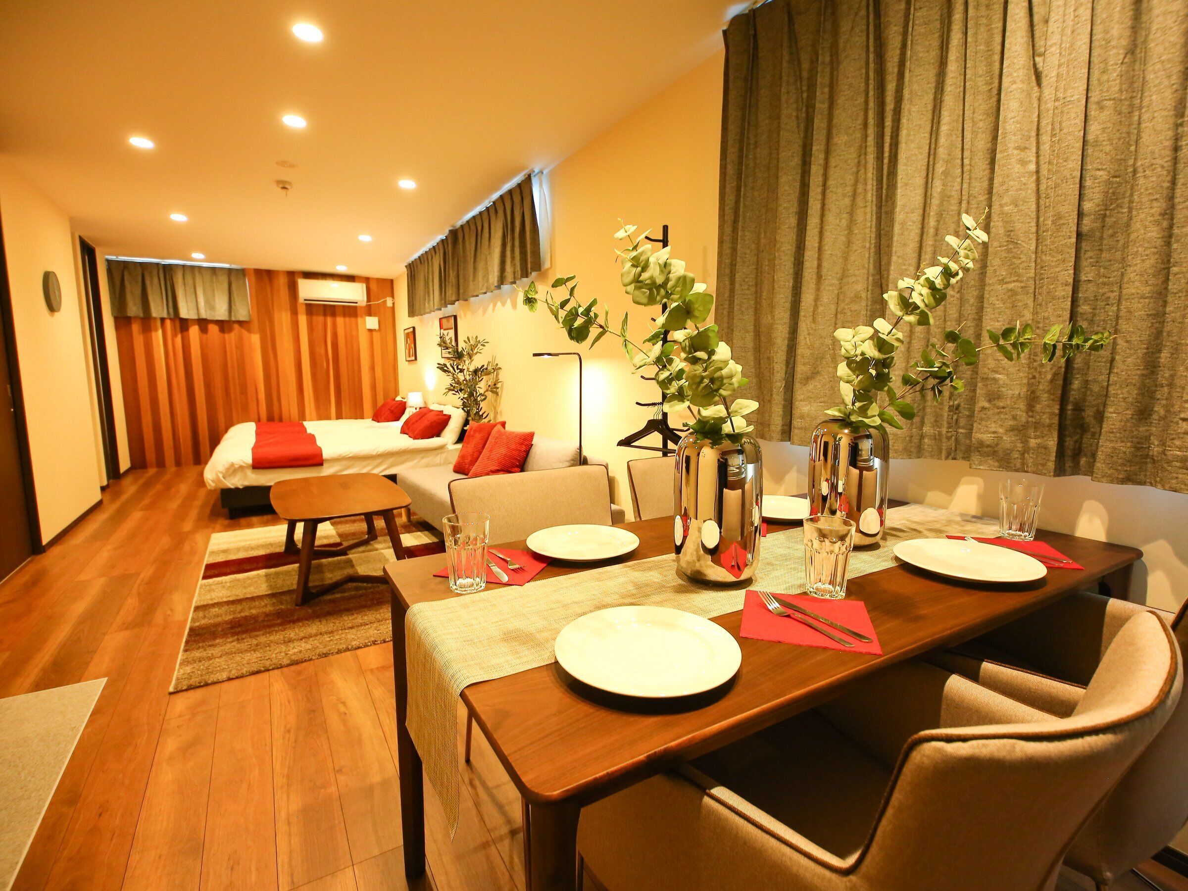Une chambre d’hôtel comprenant un coin repas, un canapé, un lit et une plante.