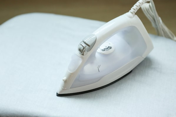 Una plancha blanca con panel de control y cable.