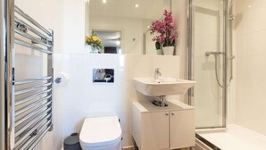 Ein modernes Badezimmer mit Toilette, Waschbecken und Dusche.