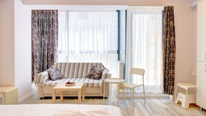 A hotel room with a sofa, a small table, a chair, and a bed.
