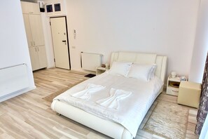 A hotel room with a large bed, a nightstand, a wardrobe, and a small seating area. - Apartamente La Butoaie (Navodari)