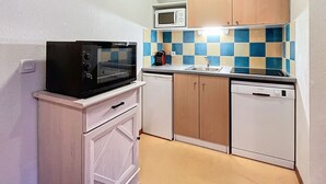 Een compacte keuken met een magnetron, een vaatwasser en een klein aanrecht.